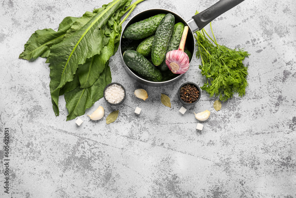Saucepan with fresh cucumbers and ingredients for preservation on light background