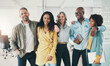© Flamingo Images - Diverse team of businesspeople laughing while standing together in an office