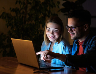 Wall Mural - business young friend night couple student laptop computer office businessman businesswoman entertainment tv watching television movie startup evening glowing screen