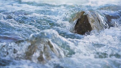 Wall Mural - Water flowing in spring river over small rock, slow motion video