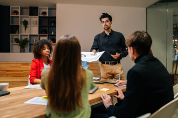 Wall Mural - Successful diverse multiracial businesspeople gather at briefing brainstorm, discuss company business ideas together. Multiethnic colleagues talk consider financial startup project at office meeting.