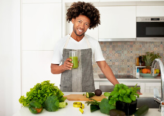 Black Man Holding Glass Of Green Vegetable Juice In Kitchen