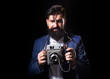 © Volodymyr - Bearded old man photographer with a large old professional camera. Portrait of man photographer with vintage retro old film camera isolated on a black background. Retro photographer.