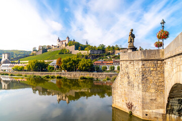 Wall Mural - View from the Alte Mainbrucke Old Bridge of the medieval Marienberg Fortress along the Main River with the St Colonatus statue in view at the Bavarian town of Wurzburg Germany.