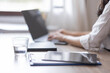 © David - Business And Education Concept. Smiling young asian woman sitting at desk working on laptop writing letter in paper documents, free copy space. Happy millennial female studying using laptop
