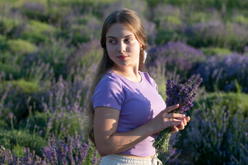 Beautiful girl in lavender flowers field. teen girl holding a lavender bouquet of flowers. Portrait of a beautiful young girl with long hair in a lavender field. Girl enjoying blooming lavender field