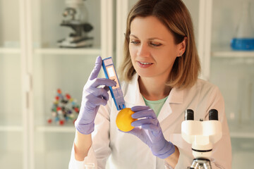 Wall Mural - Scientist examines mandarin with equipment in laboratory