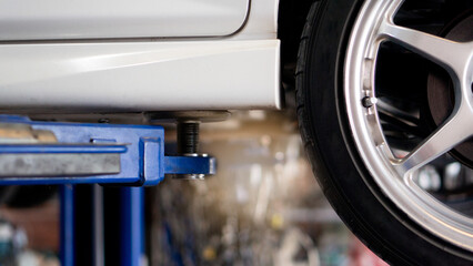 Hoy lifts cars for maintenance. and white car with half of bronze alloy wheels with low-profile tires.