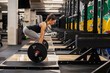 © dusanpetkovic1 - Side view of a strong woman lifting barbell in a gym.