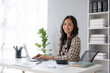 © amnaj - Happy smiling Asian businesswoman using laptop computer in the office. Beautiful young Asian female shopping or chatting online in social networks, freelance working on laptop projects.