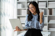 © crizzystudio - Modern working lifestyle, asian businesswoman showing happy gesture of online business success on laptop and mobile phone using internet happily in office.