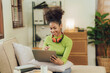 © Kritdanai - Focused young African female college student working on a laptop on living room.