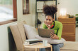 © Kritdanai - Focused young African female college student working on a laptop on living room.