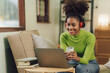 © Kritdanai - Focused young African female college student working on a laptop on living room.