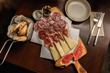 Italian antipasti cold cuts set. Cheese variety, Mediterranean olives, pickles, Prosciutto di Parma, ham, sausage, butter and bread. Spanish tapas