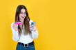 © Designerant - Easy shopping concept, portrait of caucasian beautiful girl holding smartphone and credit card for easy shopping concept. Happy face gesture. Yellow studio background, copy space. Banner, advertising.