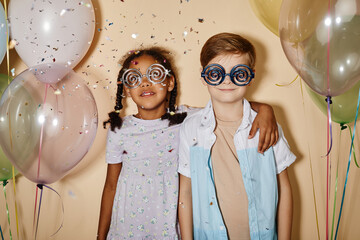 Wall Mural - Minimal portrait of boy and girl with balloons at party, wearing funky glasses glitter falling.