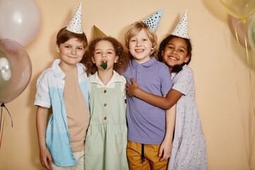 Wall Mural - Diverse group of children posing with balloons at birthday party and having fun all looking at camera