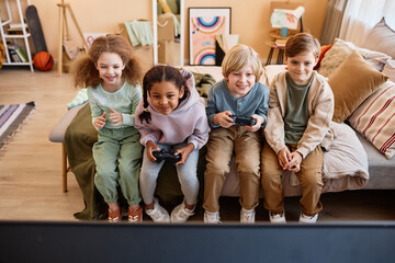 Wall Mural - High angle view at group of little children playing video games together and having fun