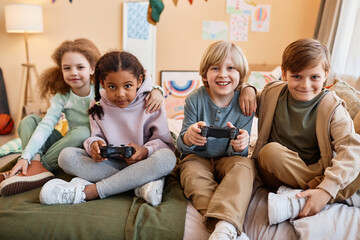 Wall Mural - Diverse group of happy little children playing video games together and having fun