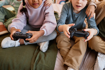 Wall Mural - Closeup of children playing videogames together and holding controllers