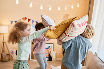 Wall Mural - Diverse group of little children enjoying pillow fight and having fun playing together