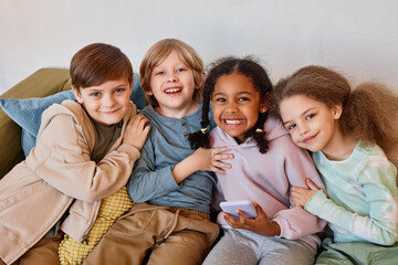 Wall Mural - Group of cheerful little kids looking at camera and smiling indoors