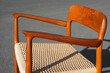 A danish mid century modern teak armchair from the 60s vintage standing in the dining living room with paper cord seat teak wood 50s 70s retro original isolated refurbished outside sunlight closeup