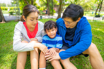 Happy Asian parent and little kids enjoy and fun outdoor lifestyle on summer vacation. Father, mother and child playing and relaxing together at park. Family relationship and health care concept.