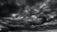 Dark Dramatic Sky With Black Stormy Clouds Before Rain Or Snow As Abstract Background, Extreme Weather, The Sun Shines Through The Clouds, High Contrast Photo