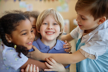 Wall Mural - Diverse group of children embracing happily while playing together and smiling