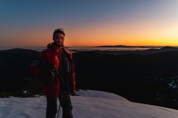 Wall Mural - Climber standing against the background of the sky at sunset.