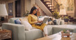 © Kitreel - Young and Beautiful Indian Woman Works Remotely From Home, Seated On A Cozy Sofa With Laptop. Productive and Efficient at Virtual Management. Browsing Internet and doing Online Shopping.