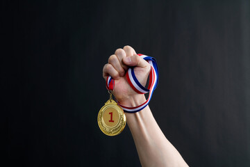 Wall Mural - Human hand holding gold medal on black background