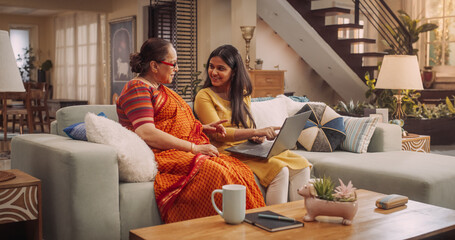 Excited Indian Mother and Daughter Using Laptop: Bonding Over Shared Interests, Doing Online Shopping for best e-Commerce Deals and Clothing Sales. Celebrating Family Togetherness. 