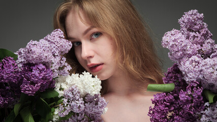 beautiful girl with blue eyes with a bouquet of lilacs on a black background in the studio