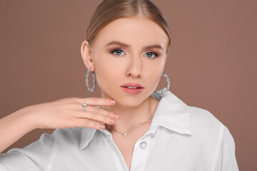 Wall Mural - Beautiful young woman with elegant jewelry on light brown background