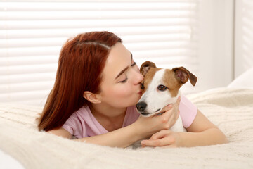 Wall Mural - Woman kissing cute Jack Russell Terrier dog on bed at home