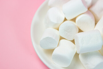 Wall Mural - Plate with vanilla marshmallows on a pink background.