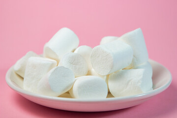 Wall Mural - Plate with vanilla marshmallows on a pink background.