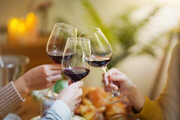 Cheerful friends enjoying home Birthday holiday party. Asian Friends cheering drinking red wine celebrating Christmas or New Year party