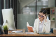 © Songsak C - An Asian businesswoman is serious about reading a book and works hard until the headache.