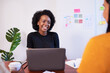 © Meeko Media - Black woman with afro smiles at meeting, development team coding, laptop
