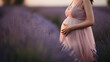 A pregnant woman in a pink dress stands in a field of lavender., generative ai