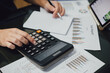 © nateejindakum - Businessman hands with calculator at the office and financial data analyzing business result and tax management. Finance accounting and economy concept.
