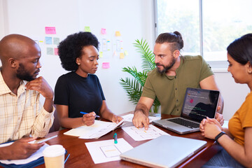 diverse development team discusses code during code review meeting, programming