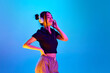© master1305 - Portrait of beautiful young korean girl listening to music in headphones against blue studio background in neon light. Concept of emotions, facial expression, youth, lifestyle, inspiration, sales, ad