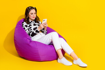 Sticker - Full length photo of millennial girl sit bean bag chair using smart gadget isolated on vibrant color background