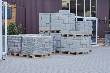 Poster - heaps of new white bricks and gray paving slabs on a pallet outdoors in a warehouse against a wall