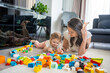 © dtatiana - Little girl play with constructor toy on floor in home with mom or woman babysitter, educational game, family at home spend leisure activities time together concept